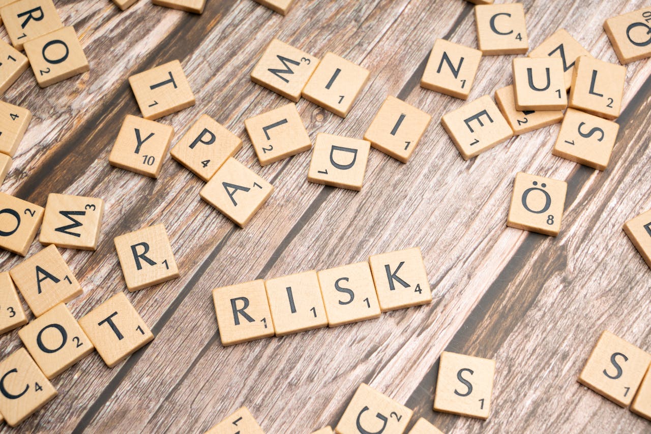 Scrabble tiles spelling out risk scattered on a rustic wooden background, symbolizing uncertainty.